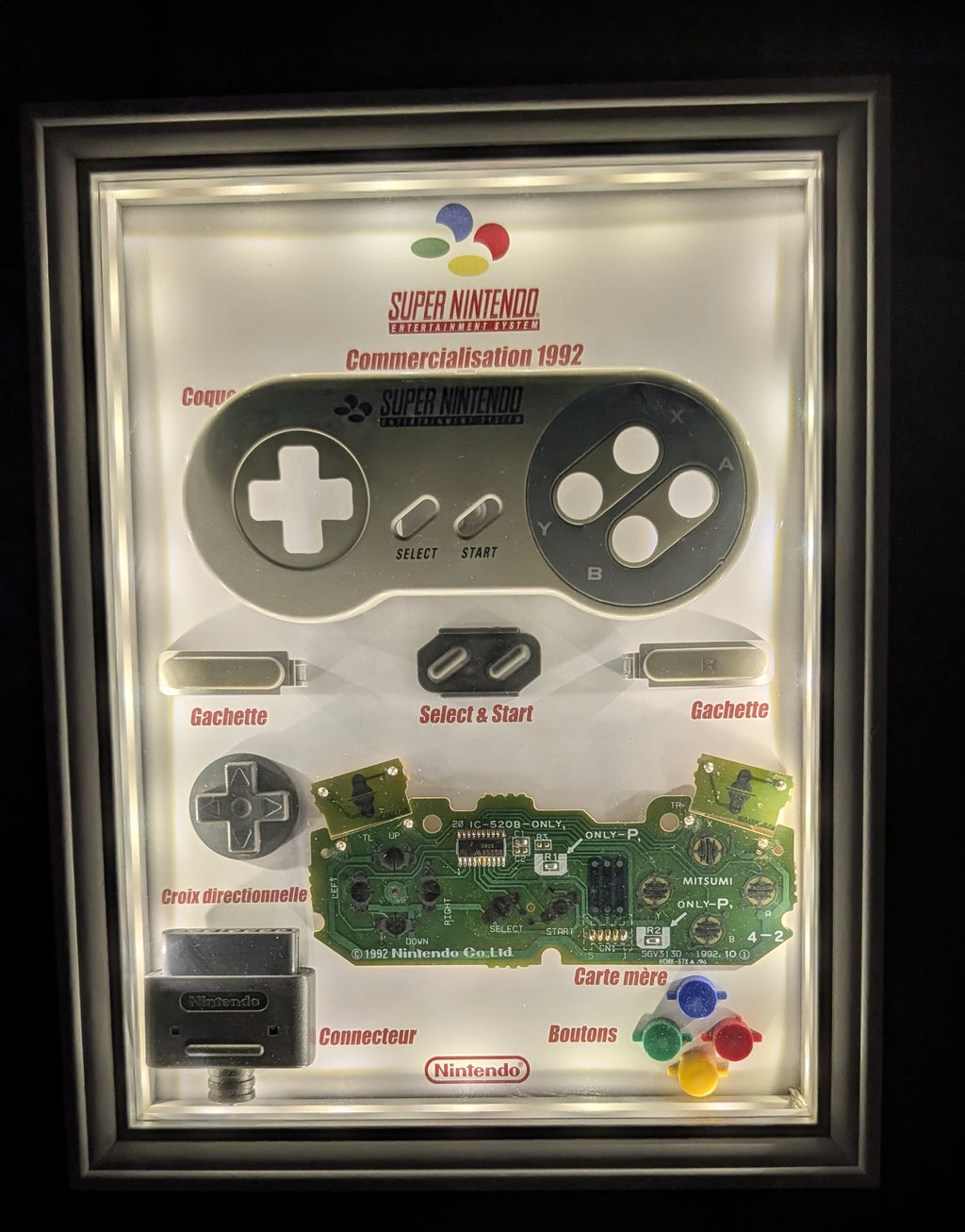 Diorama manette Super Nintendo SNES démontée avec éclairage LED intégré dans un cadre décoratif